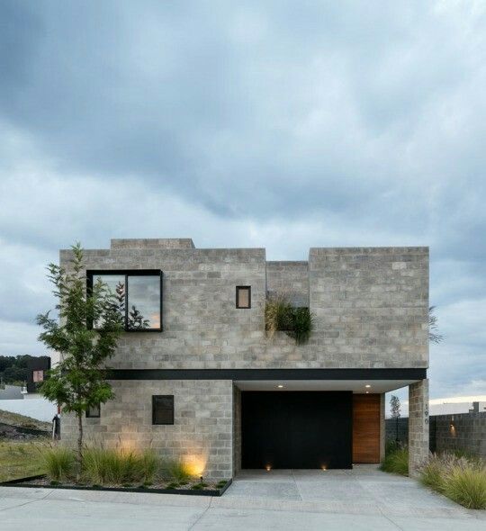 a concrete house with two garages and plants on the roof, along side it