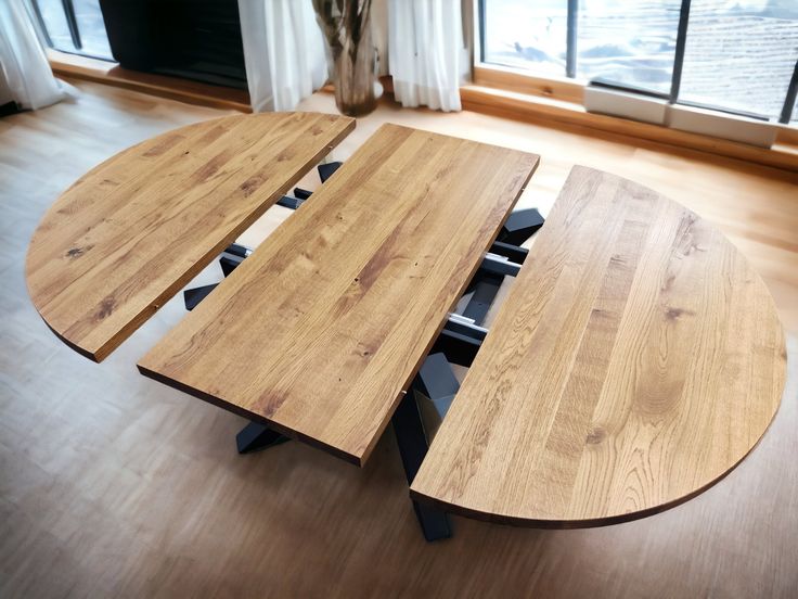 two wooden tables sitting on top of a hard wood floor next to a large window