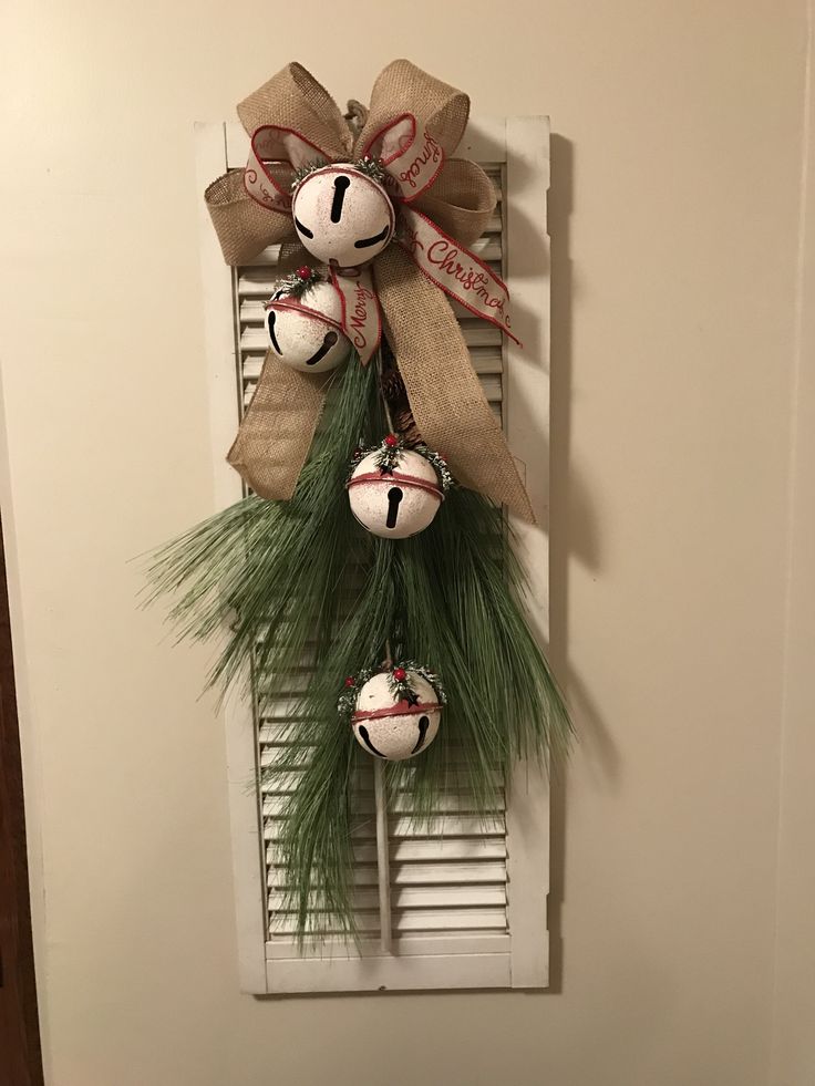 a door hanger decorated with christmas balls and pine needles, tied in burlocks