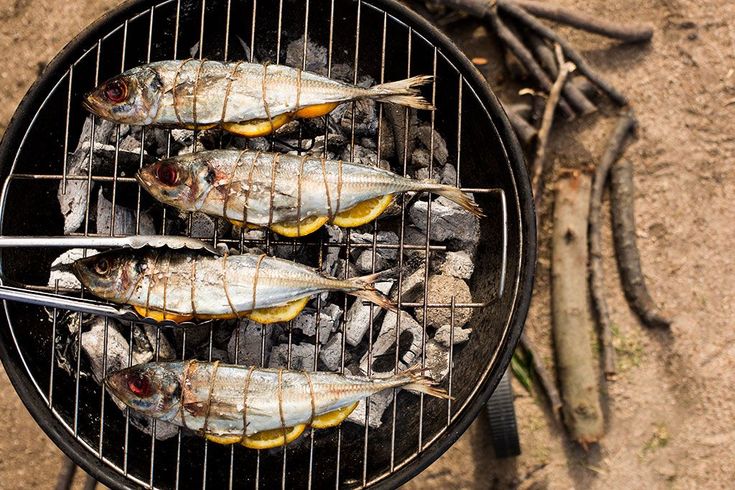 three fish are cooking on the grill with tongs