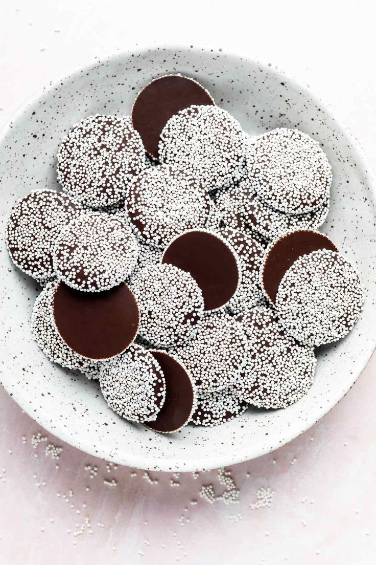 a white bowl filled with chocolate covered donuts