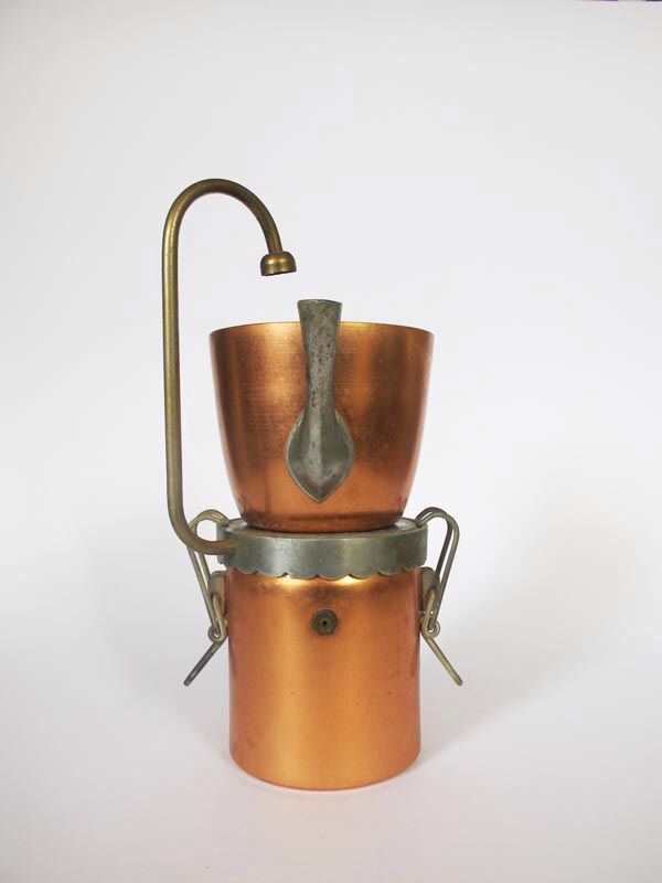 an old fashioned copper pot is sitting on a white surface with a metal spigot attached to it