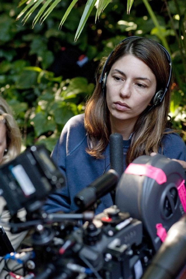 two women with headphones on sitting next to each other in front of camera equipment