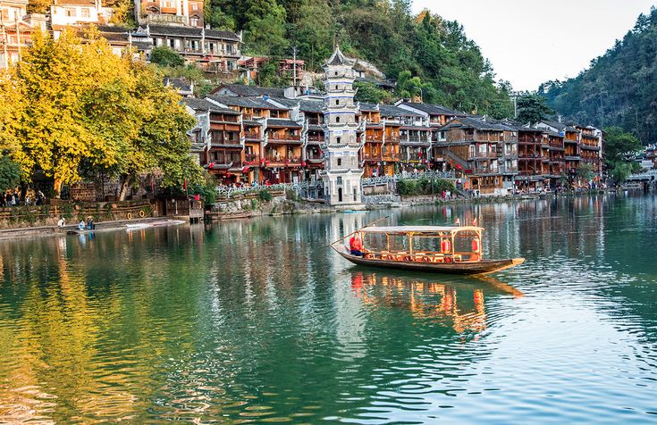 a boat floating on top of a lake next to tall buildings