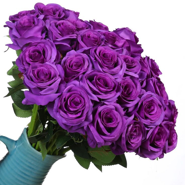 a blue vase filled with purple roses on top of a table