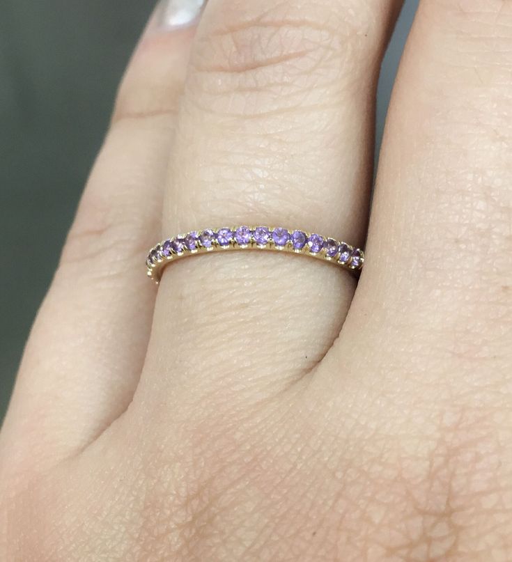 a woman's hand with a yellow and purple diamond ring on her left finger