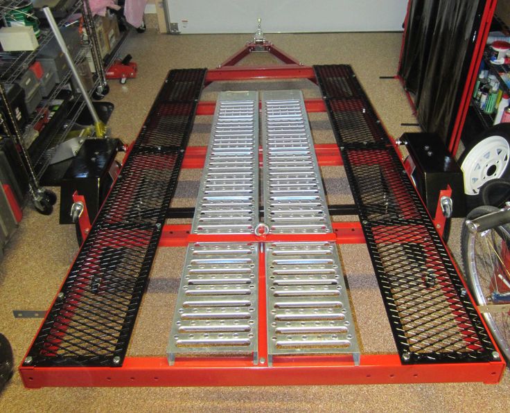 a red dolly with two ramps on it in a room filled with other items and tools