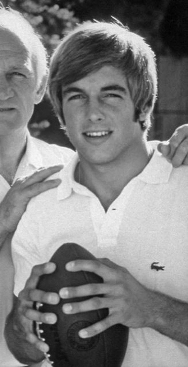 an older man holding a football next to a younger man