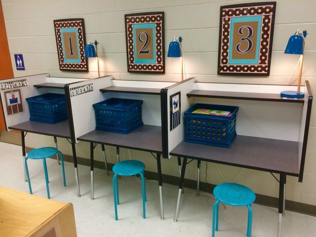 three desks with blue bins on them in a classroom