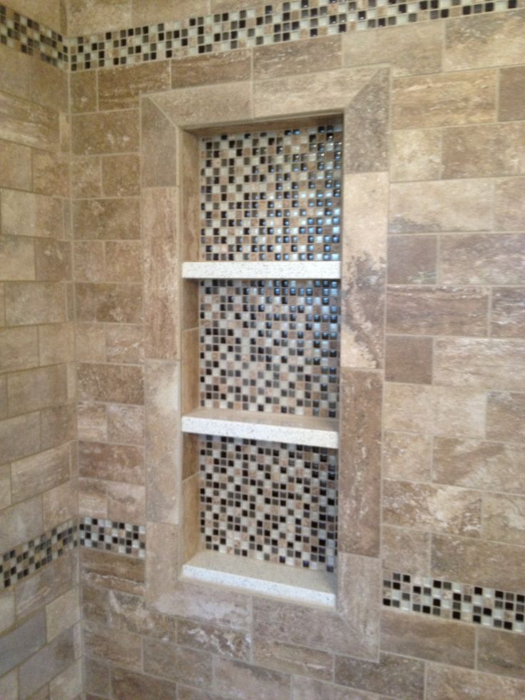 a bathroom with tiled walls and shelves in the shower area, along with tile flooring