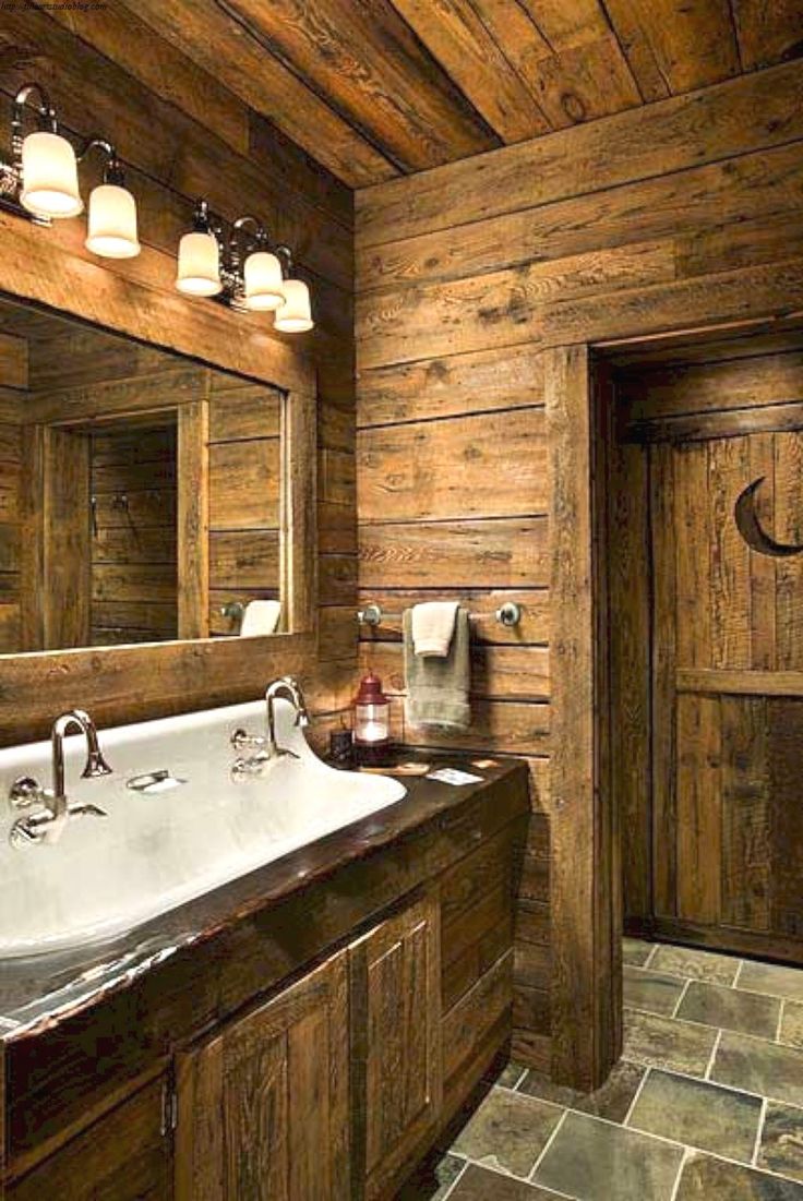 a bathroom with wooden walls and flooring has two sinks in the middle, one on each side