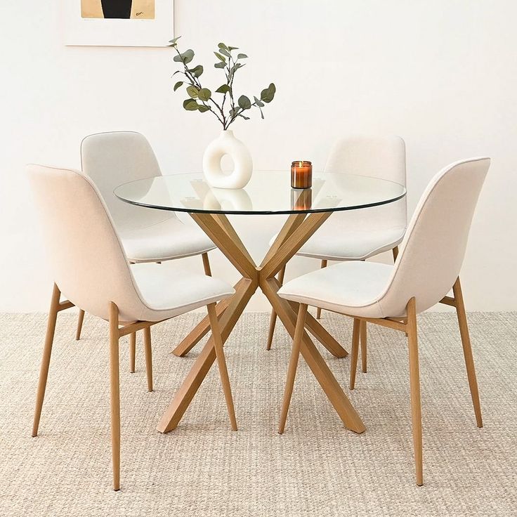 a glass table with four chairs around it and a vase filled with flowers on top