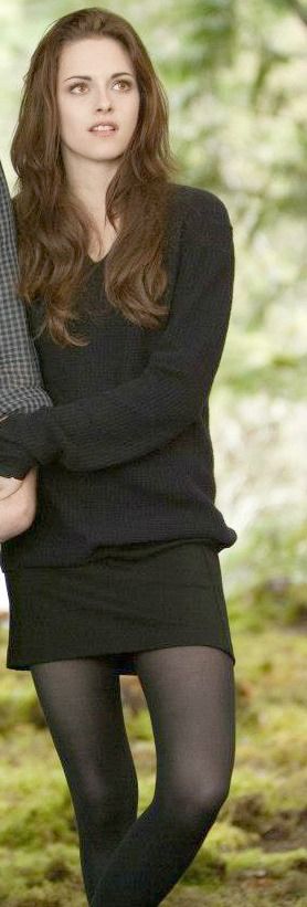 a woman in black is holding a book and posing for the camera with her hands on her hips