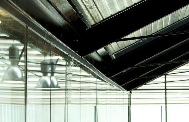 the inside of a building with glass walls and metal fixtures on the ceiling is shown