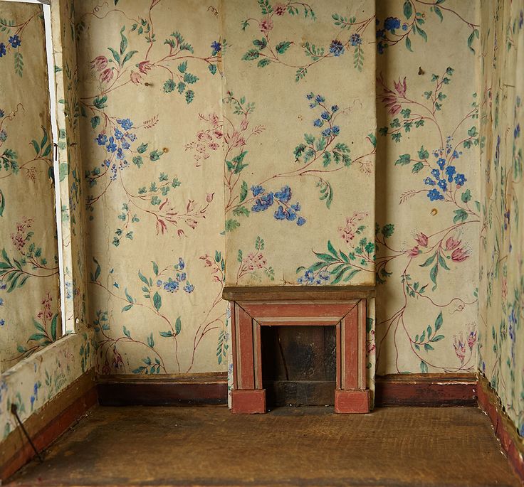 an empty room with floral wallpaper and a small fire place in the corner on the floor