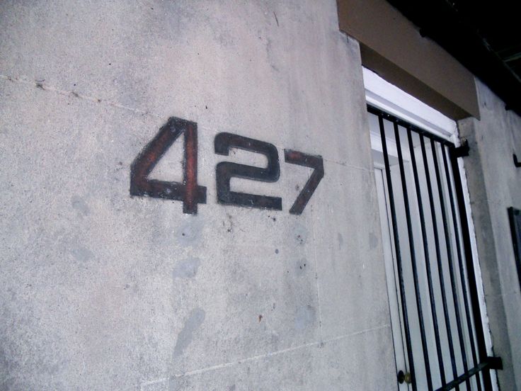 graffiti on the side of a building that says 427 in large letters and is next to a gate