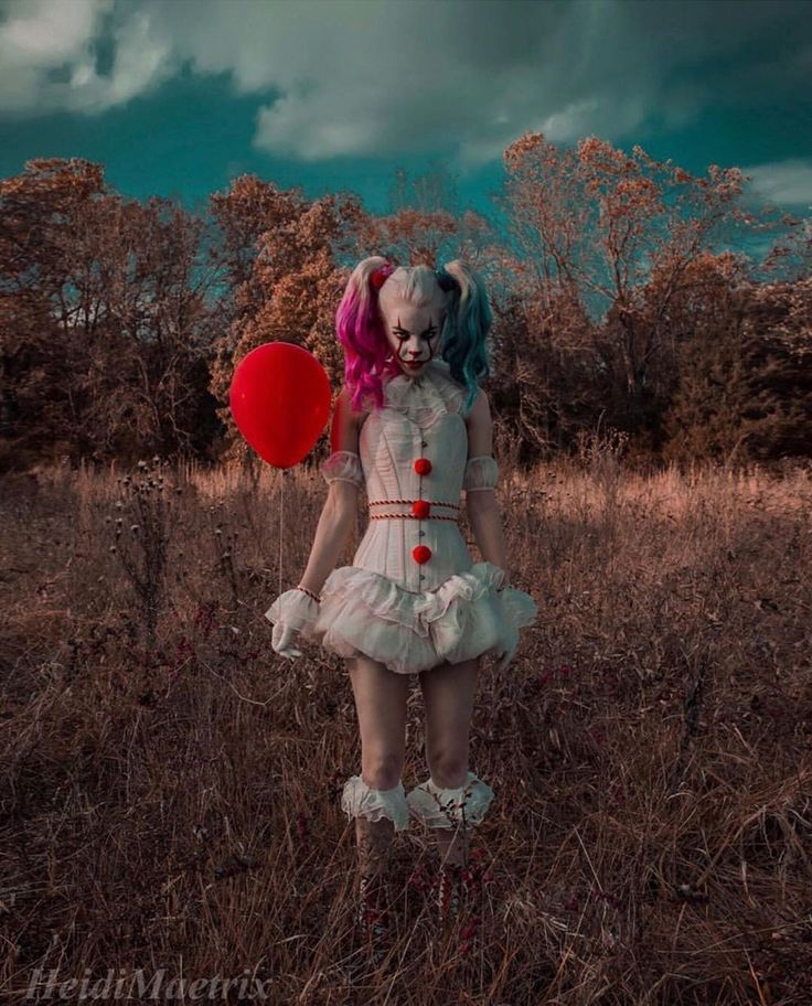 a creepy doll holding a red balloon in a field