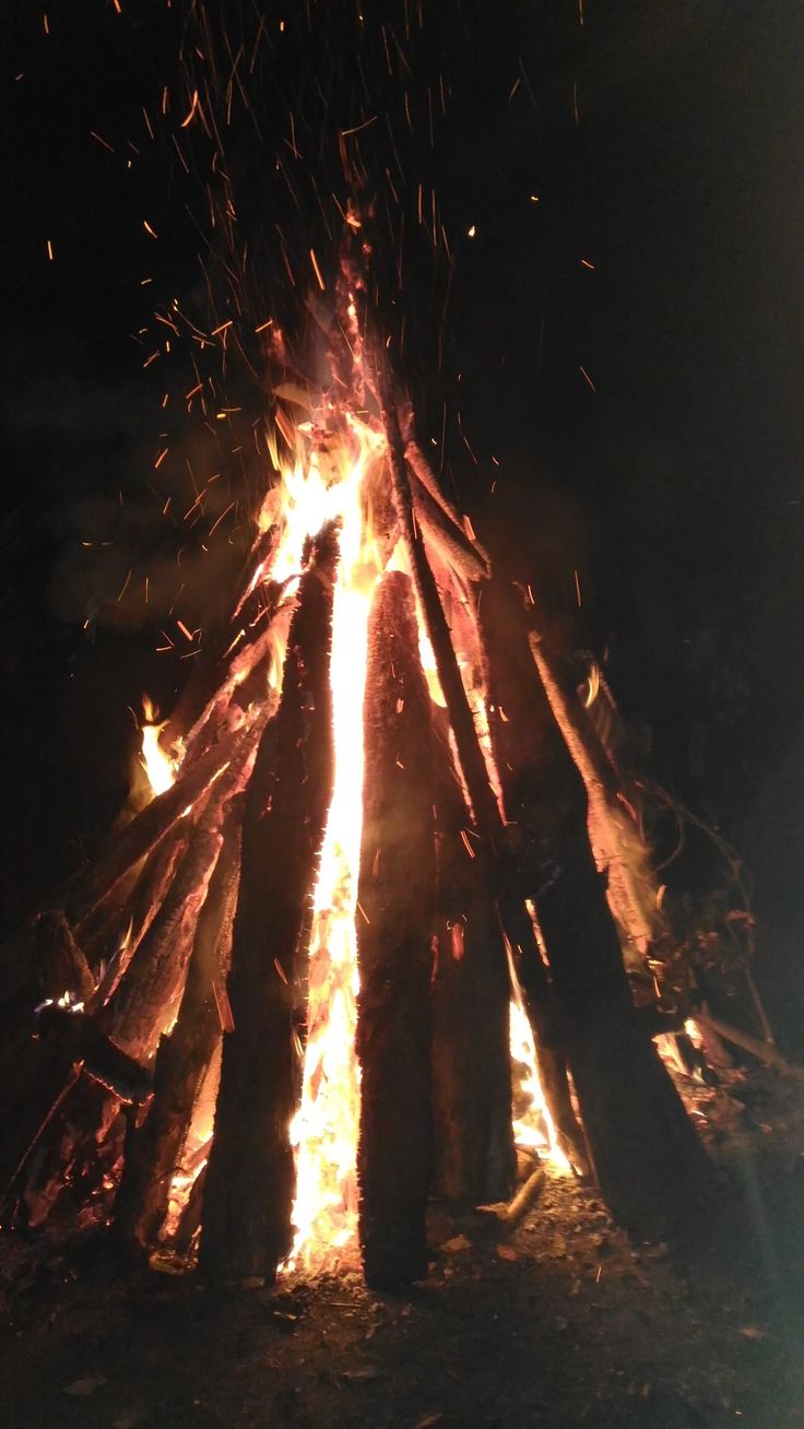 the fire is glowing brightly at night with lots of sticks sticking out of it's sides