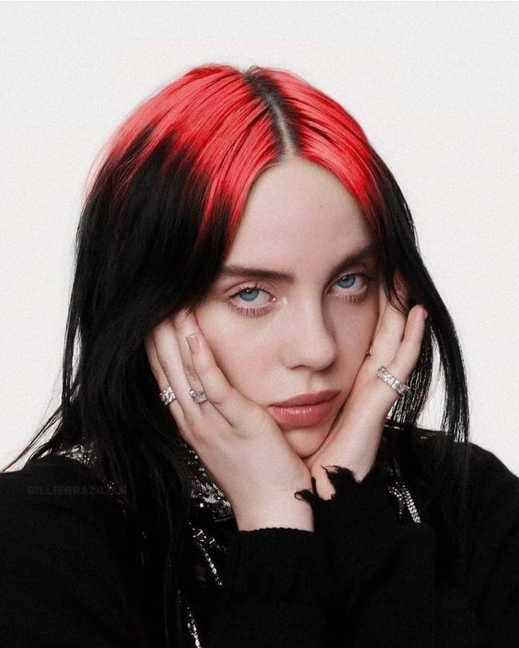 a woman with red hair and piercings posing for a photo in front of a white background