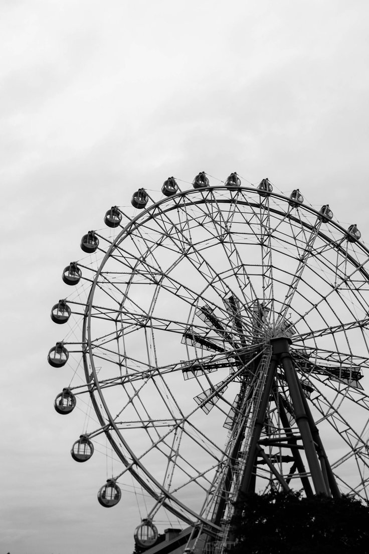 a ferris wheel in black and white against a cloudy sky