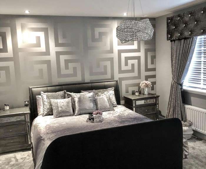 a bedroom decorated in gray and silver with a bed, nightstands, lamps and curtains