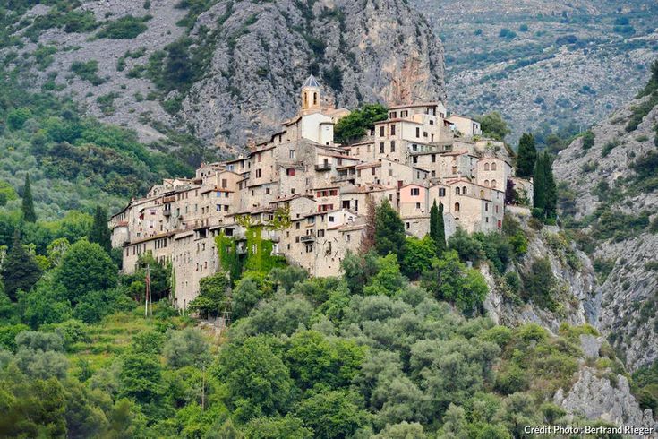 an old village built into the side of a mountain surrounded by trees and greenery