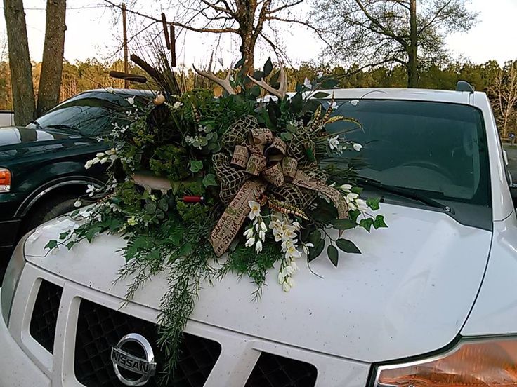 the truck is decorated with greenery and bows on it's hood, along with other vehicles