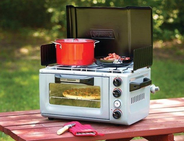 an oven sitting on top of a picnic table with pots and pans in it