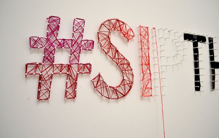 the letters are made out of red and black wire, which is attached to a white wall