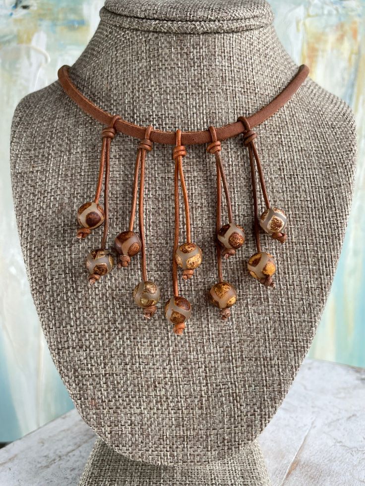 Beautiful Copper, Gold, Sienna Brown Crackled Agate Glass beads. I love the fun casual boho look of this necklace. I chose a  distressed sienna brown thick leather cording for the base.  There are 5 double strands of leather attached to create dangles for the beautiful agate beads. The beads are unique in the design and multiple colors you will see.  They are an opaque glass with a crackled look. The colors include sienna brown to match the leather. You will also see copper, gold, tan, and taupe Casual Brown Jewelry For Festivals, Casual Leather Jewelry For Festivals, Bohemian Agate Jewelry With Adjustable Cord, Adjustable Brown Necklace With Waxed Cord, Adjustable Brown Waxed Cord Necklace, Casual Brown Necklace With Adjustable Cord, Brown Artisan Jewelry With Dangling Beads, Artisan Brown Jewelry With Dangling Beads, Brown Necklace With Adjustable Cord For Festivals