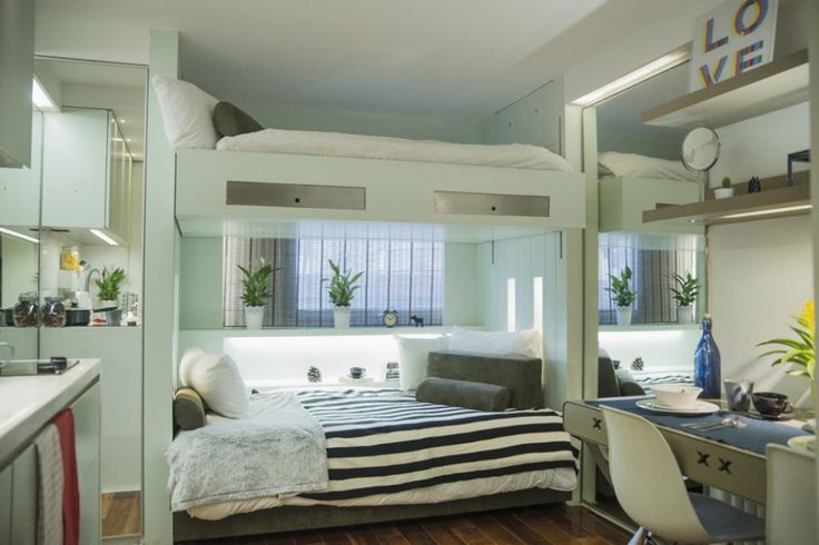 a bedroom with bunk beds, desk and mirror in it's corner area next to a sink