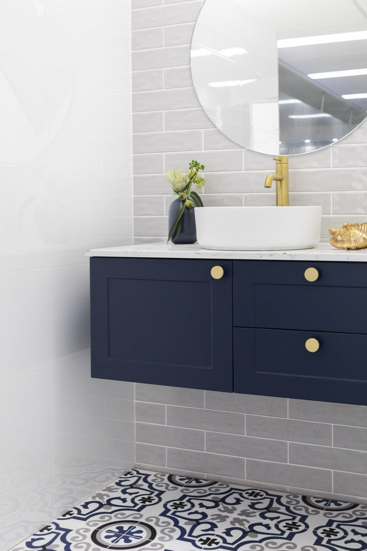 a white sink sitting under a mirror next to a blue cabinet and counter top in a bathroom