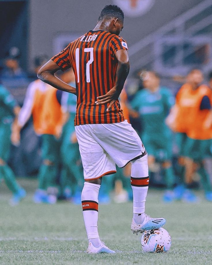 a man standing on top of a soccer field next to a white and orange ball