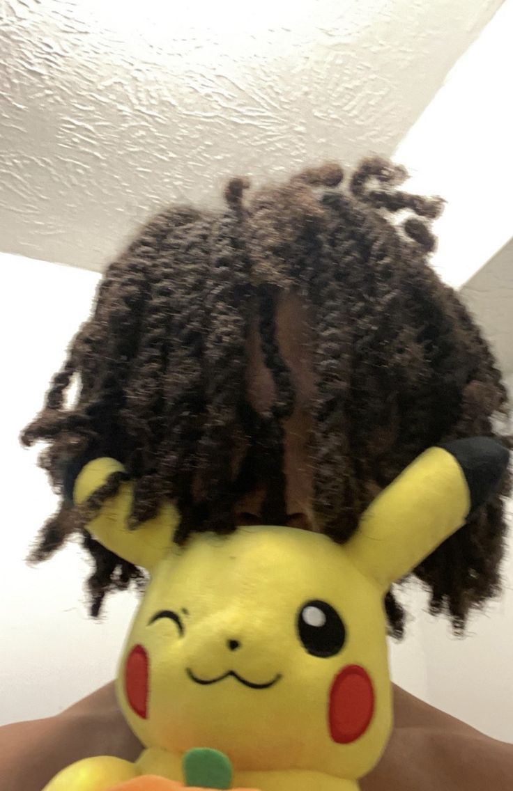 a person with dreadlocks and a stuffed animal in front of their head is wearing a pikachu costume