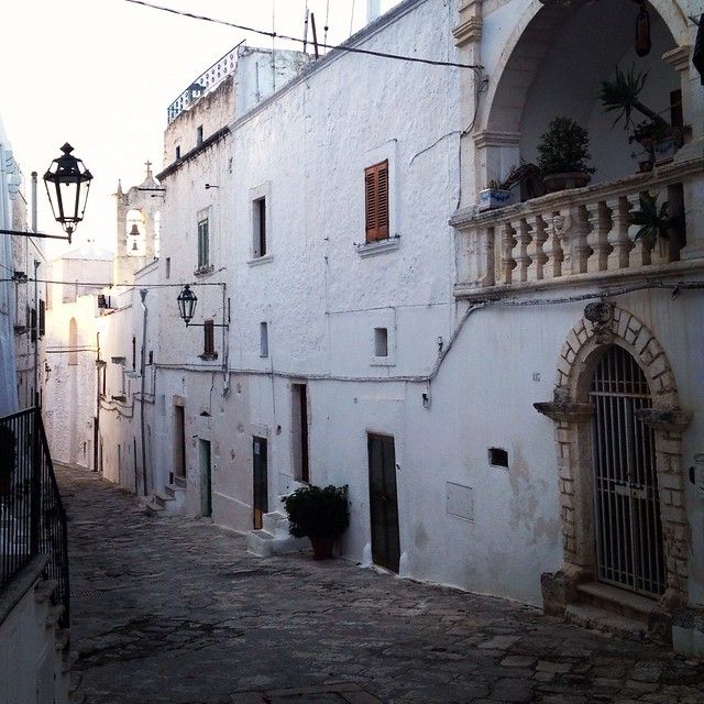 an alley way with white buildings and stone pavemented walkways in the foreground