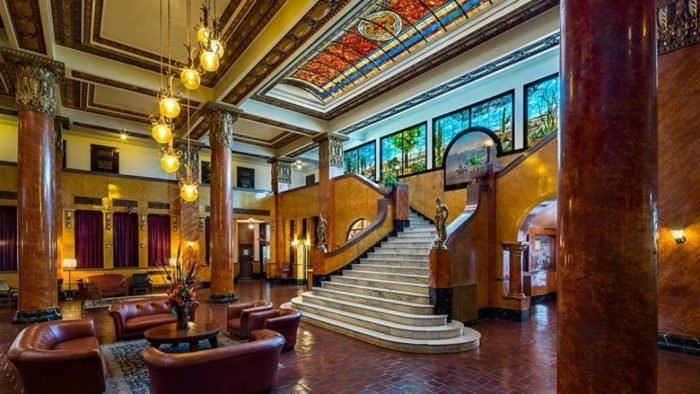 the lobby is decorated with stained glass windows and chandeliers, along with leather chairs