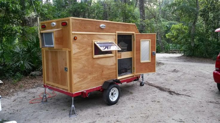 a small trailer is parked on the side of a road with trees in the background