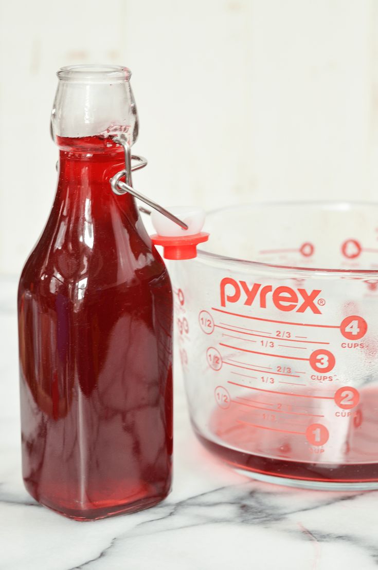 a bottle of syrup next to a measuring cup