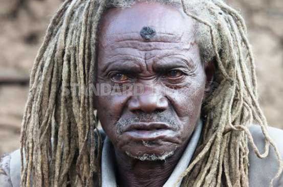 an old man with dreadlocks looks at the camera