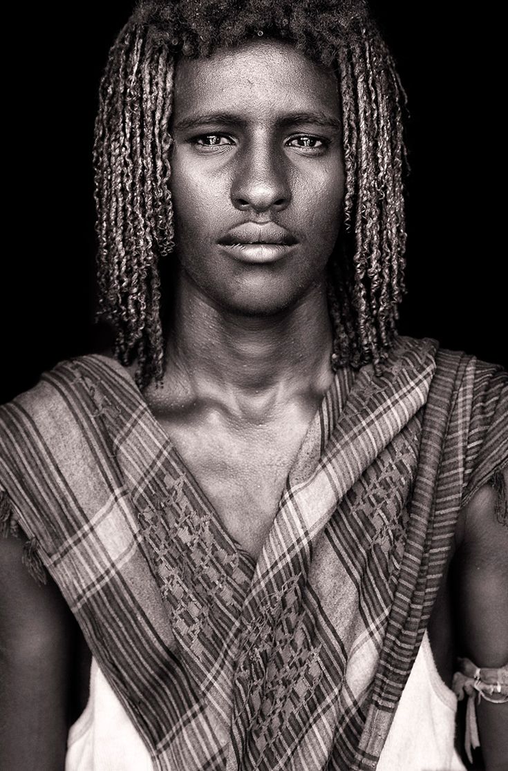 a black and white photo of a man with dreadlocks on his head wearing a scarf