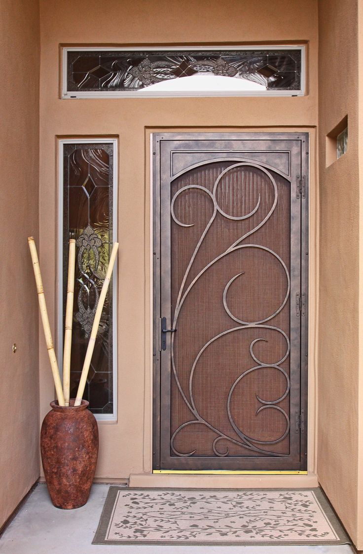 the front door is decorated with an intricate iron design and bamboo reeds for decoration