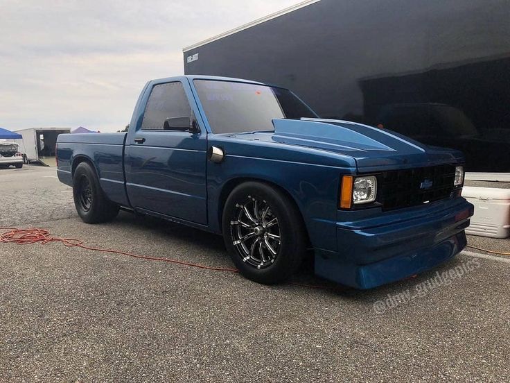 a blue pick up truck parked in front of a trailer