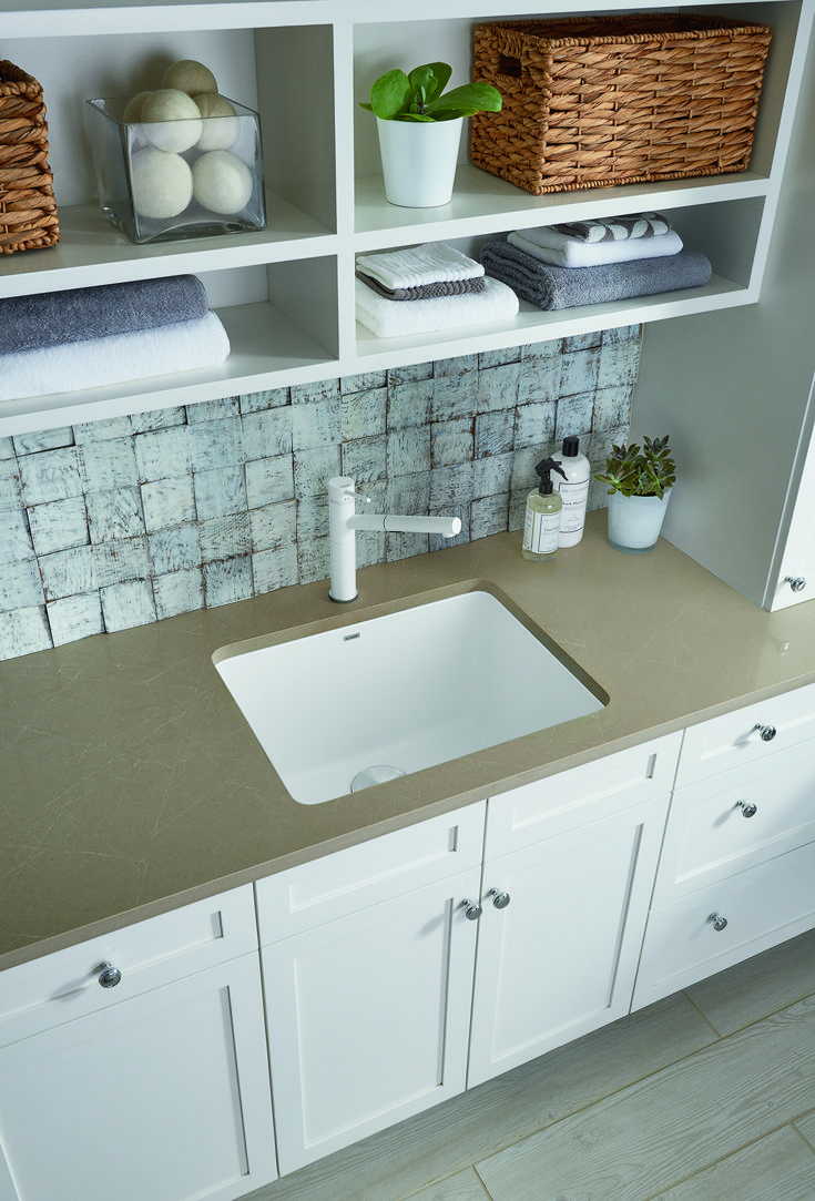 a white sink sitting under a bathroom mirror next to a shelf filled with towels and other items