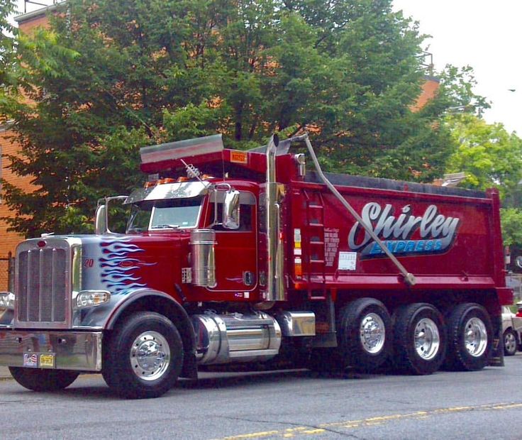 a red semi truck parked in front of a brick building with the word slinkey on it's side