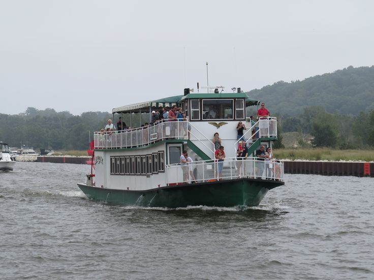 a large white and green boat with people on it's deck in the water