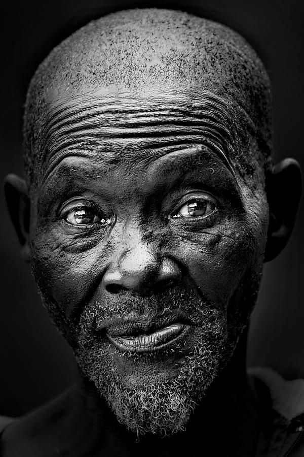 an older man with wrinkles on his face, looking at the camera in black and white