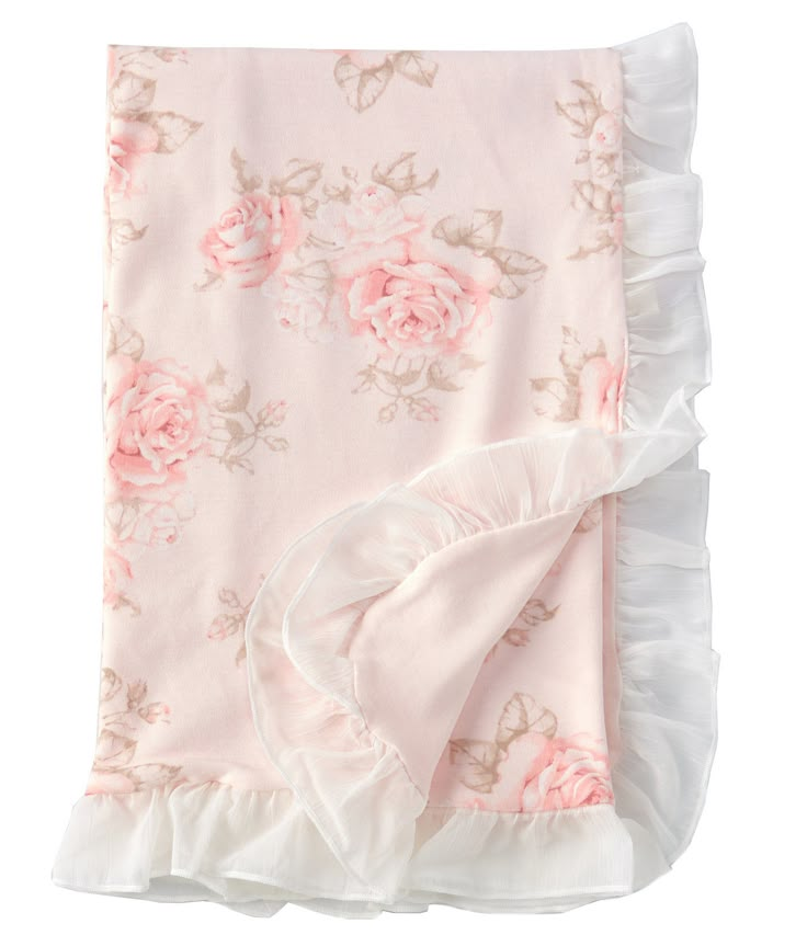 a pink blanket with white ruffles and roses on the bottom is laying down