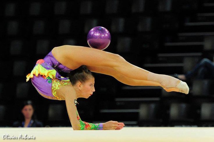 a woman doing a handstand on the floor with a ball above her head