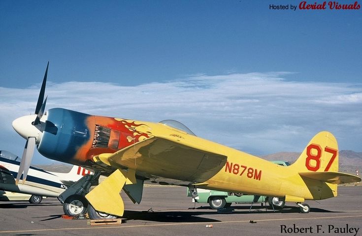 an old yellow airplane is parked on the tarmac with other planes in the background