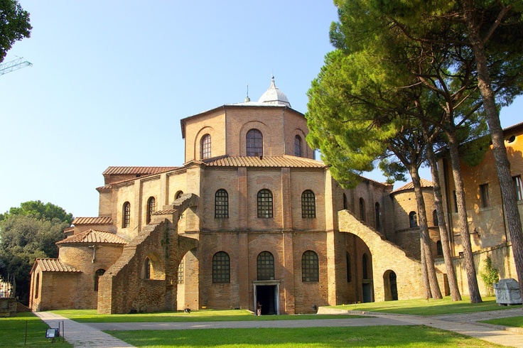 an old building is shown with trees in the foreground and grass on the ground